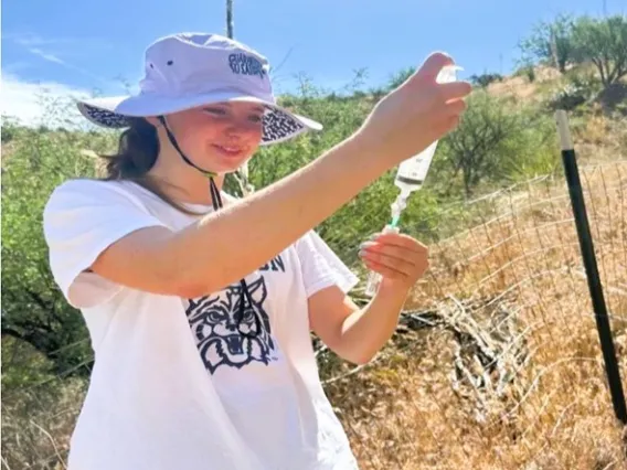 Picture of Jordan in a field, pouring water into a vial