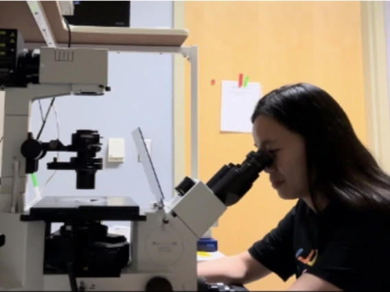 Picture of Truc Le looking through a microscope