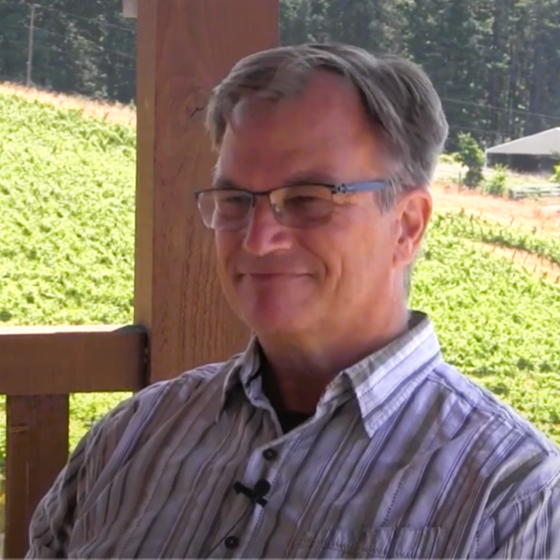 Picture of David Bellows sitting on a porch next to a vineyard