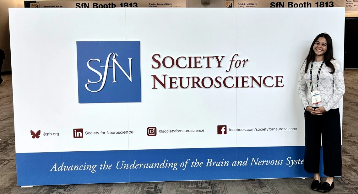 Ava Pal poses in front of the Society for Neuroscience sign