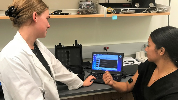 Picture of Paige Rudy explaining tasks and data collection to a fellow student in front of a computer 