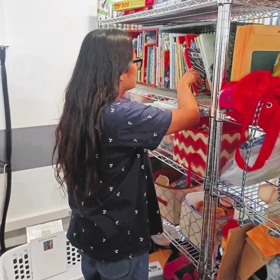 Picture of Mohima pulling out a book from a bookshelf