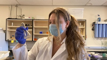 Picture of Sophia Marcinowski holding a flask at the lab bench