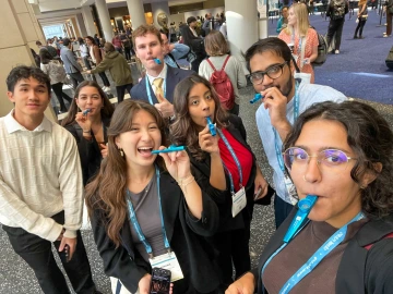 Picture of group of students in conference hall, playing kazoos